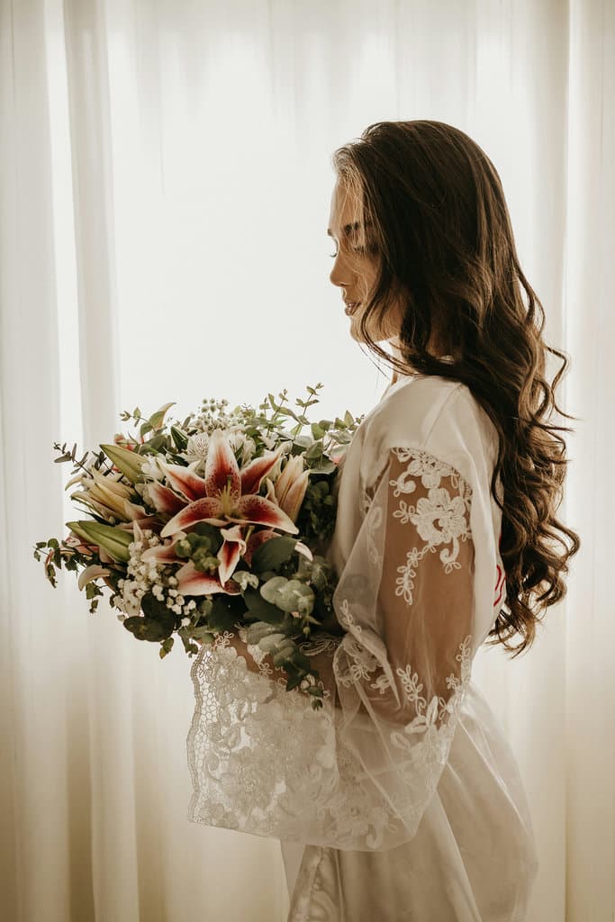 The bride with the wedding bouquet against the background of a drawn window through which light shines.