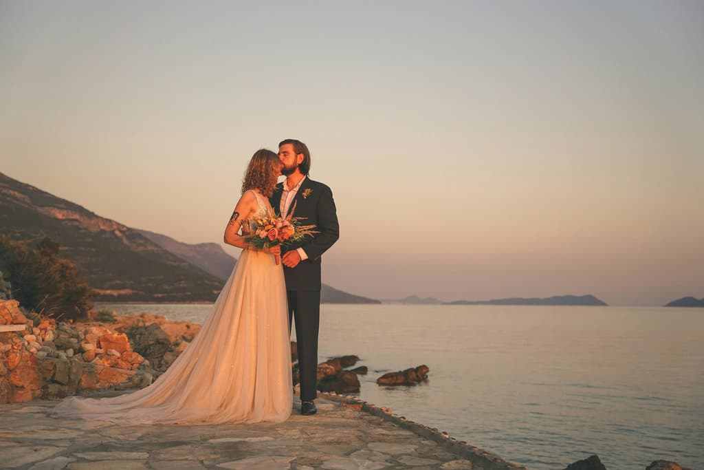 Newlyweds by the seaside against a mountain backdrop