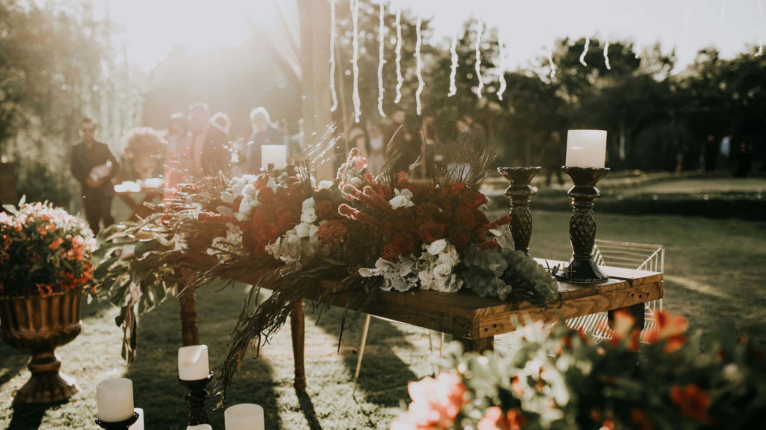 Blumen und Kerzenständer auf einem Tisch im Garten vor verschwommenem Hintergrund